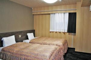 ein Hotelzimmer mit 2 Betten und einem Fenster in der Unterkunft The Celecton Takamatsu in Takamatsu