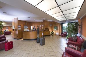 a man standing at a counter in a lobby with luggage at Hotel La Pioppa in Bologna