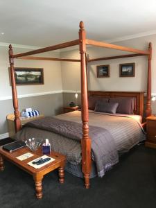 a bedroom with a wooden bed and a table at Alpine Springs Motel in Hanmer Springs