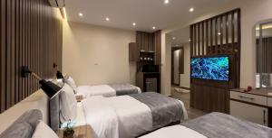 カイロにあるSky Pyramids Viewのベッド3台、薄型テレビが備わるホテルルームです。