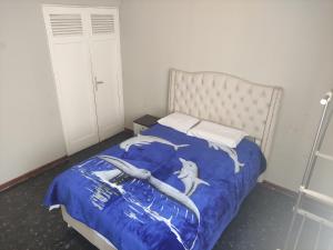Una cama con un edredón azul con delfines. en Residencial 200 Casas, en Tacna