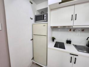 a white kitchen with a refrigerator and a sink at Enjoy BGC Sunset and Golf Course View 2 BR Loft with 100mbps Internet Connection in Manila