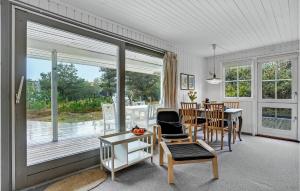 BjerregårdにあるAmazing Home In Hvide Sande With 3 Bedrooms And Wifiのリビングルーム(テーブル、椅子、大きな窓付)