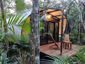 una pequeña casa en el bosque con una terraza de madera en Zil-Kaab Hidden Glamping Village, en Tulum