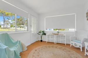 ein weißes Zimmer mit 2 Stühlen, einem Tisch und einem Fenster in der Unterkunft Waterfront Fishermans Cottage in Erowal Bay