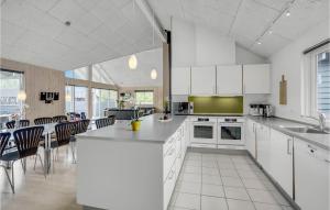 ノーポにあるCozy Home In Nordborg With Kitchenの白いキャビネット、テーブルと椅子付きのキッチンが備わります。