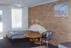 a room with a bed and a table and chairs at Shady Rest Motel in Gympie