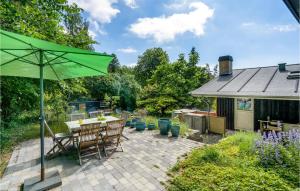 um pátio com uma mesa e um guarda-chuva verde em Gorgeous Home In Holbk With Kitchen em Holbæk
