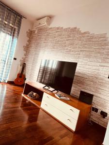 a living room with a tv and a brick wall at Appartamento tra Aeroporto DaVinci e Fiera di Roma in Fiumicino