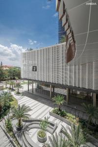 a large white building with palm trees in a courtyard at Leo House - The Song Building 28 Thi Sách in Vung Tau