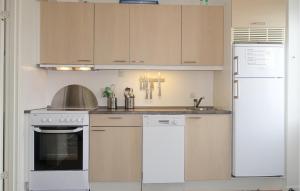 a kitchen with white appliances and wooden cabinets at 2 Bedroom Lovely Apartment In Allinge in Allinge