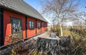 a red house with a chair in front of it at 2 Bedroom Awesome Home In stermarie in Østermarie