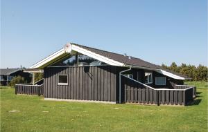 a black house with a fence in the grass at Stunning Home In Lkken With 5 Bedrooms, Sauna And Wifi in Løkken