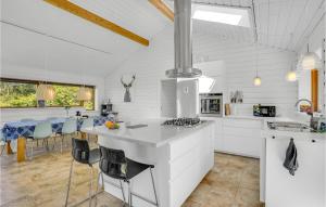 a white kitchen with a counter and chairs in it at Three-Bedroom Holiday Home In Farevejle in Fårevejle