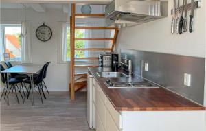 a kitchen with a sink and a table and a clock at Kbmandsgrden in Gudhjem