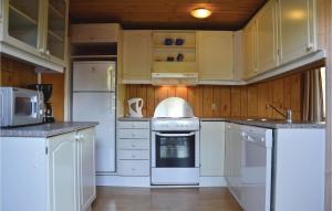 a kitchen with white appliances and wooden cabinets at Holiday Home Lyngshuse Herning V in Kølkær +5 photos