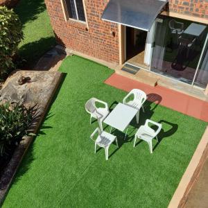 eine Terrasse mit einem Tisch und Stühlen auf Gras in der Unterkunft Rilli's Inn Apartment in Mtunzini