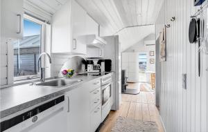 Una cocina con gabinetes blancos y un fregadero y una ventana. en Stunning Home In Fanø With Kitchen, en Fanø