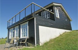 BagenkopにあるStunning Home In Bagenkop With 3 Bedrooms And Wifiの丘の上に窓と椅子のある黒い家