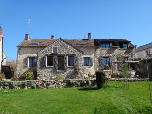 une grande maison en pierre avec une cour verdoyante dans l'établissement La maison du Fargis, à Auffargis