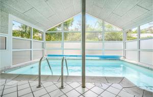 an indoor swimming pool with an arched window at Beautiful Home In Glesborg With Sauna, Wifi And Outdoor Swimming Pool in Fjellerup Strand