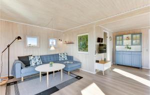 BjerregårdにあるNice Home In Hvide Sande With Saunaのリビングルーム(青いソファ、テーブル付)