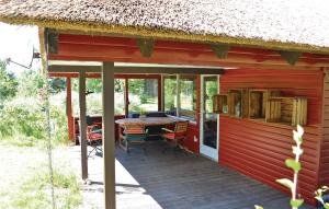 een rood huis met een houten terras met een tafel bij 4 Bedroom Awesome Home In Rm in Vesterhede