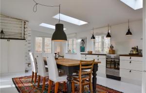 een keuken met een houten tafel en witte stoelen bij Stunning Home In Grsted With Wifi in Græsted