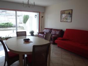 a living room with a table and a red couch at Le Moulin des Prés avec terrasse in Vesoul