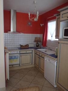 eine Küche mit roten Wänden, einer Spüle und einer Mikrowelle in der Unterkunft Le Moulin des Prés in Vesoul