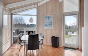 a dining room with a table and chairs and a large window at Nice Home In Grenaa With Kitchen in Stokkebro