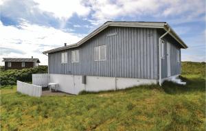 un bâtiment gris et blanc sur un champ herbeux dans l'établissement Karin, à Fanø