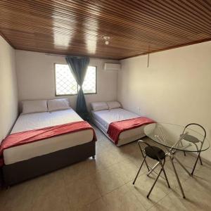 1 dormitorio con 2 camas y mesa de cristal en Casa Salmón Confortable Casa Completa, en Valledupar