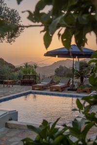 una piscina con bancos y sombrillas al atardecer en Cretan Nature Villa Alexandra, en Zarós