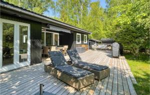 a wooden deck with two chairs and a table at Amazing Home In Aakirkeby With House Sea View in Vester Sømarken