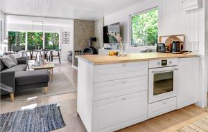 a kitchen with white cabinets and a living room at Amazing Home In Aakirkeby With House Sea View in Vester Sømarken