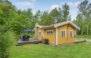 a small yellow cabin with a deck in the yard at Baluka in Bedegård