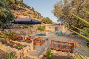 un patio con sombrilla, sillas y piscina en Cretan Nature Villa Alexandra, en Zarós