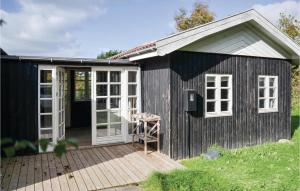 KnebelにあるNice Home In Knebel With Kitchenの白い窓と木製のデッキが備わる黒小屋