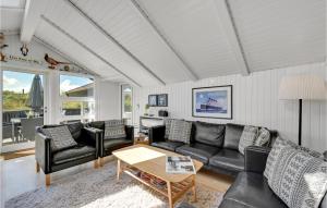 sala de estar con mesa y muebles de cuero negro en Cozy Home In Vejers Strand With Outdoor Swimming Pool, en Vejers Strand
