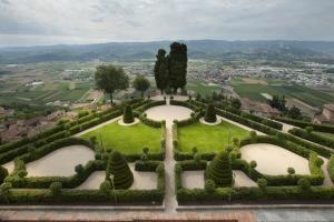 a garden with hedges and a view of a city at Castello di Guarene in Guarene