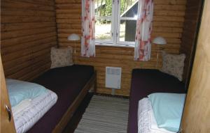 two beds in a log cabin with a window at Holiday Home Ridderstien in Spidsegård
