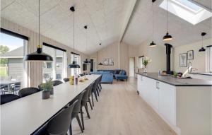 a kitchen and living room with a long counter and chairs at Amazing Home In Vggerlse With Sauna in Marielyst