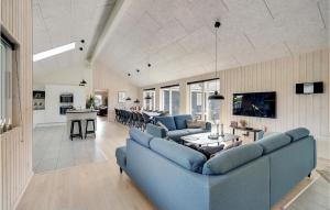 a living room with blue couches and a kitchen at Amazing Home In Vggerlse With Sauna in Marielyst
