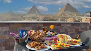 カイロにあるSky Pyramids Viewのピラミッドを背景に食べ物が詰まったテーブル