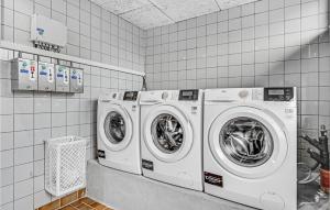 two washing machines in a white tiled laundry room at 2 Bedroom Amazing Home In Roslev in Sallingsund