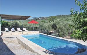 a swimming pool with chairs and a red umbrella at Nice Home In Montefrio With 4 Bedrooms, Private Swimming Pool And Outdoor Swimming Pool in Cortijo de los Gitanos
