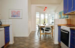 ヒアツハルスにあるBeautiful Home In Hirtshals With Sauna, Wifi And Indoor Swimming Poolのキッチン(青いキャビネット、テーブル、椅子付)