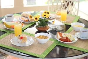 a table topped with plates of food and orange juice at Pousada Recanto do Sal in Salinópolis