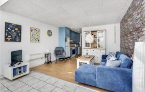 Cozy Apartment In Rm With Kitchen في رومو كيركيبي: غرفة معيشة مع أريكة زرقاء وتلفزيون
